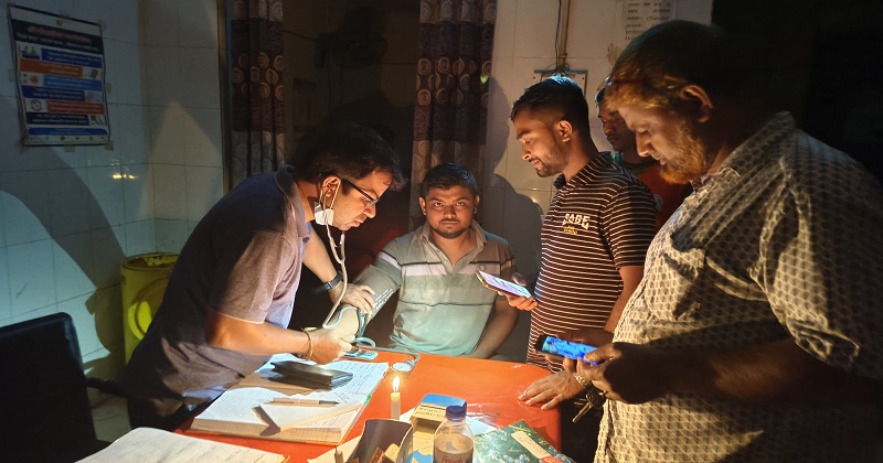 মোমবাতির আলোয় চিকিৎসা দিচ্ছেন ডাক্তার। ছবি : খোলা কাগজ