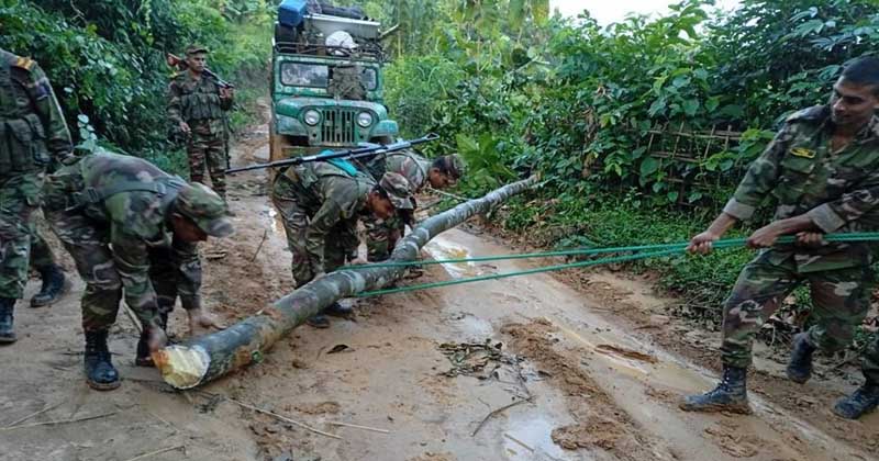 সেনা সদস্যরা গাছের গুড়ি ও বাঁশ অপসারণ করে সড়ক যোগাযোগ স্বাভাবিক করেন